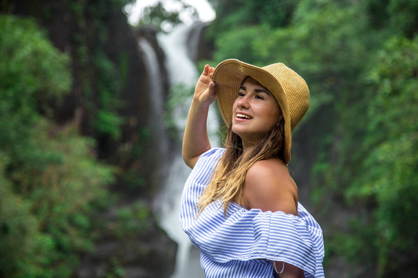 girl in hat looking at the waterfall - Фото, изображение