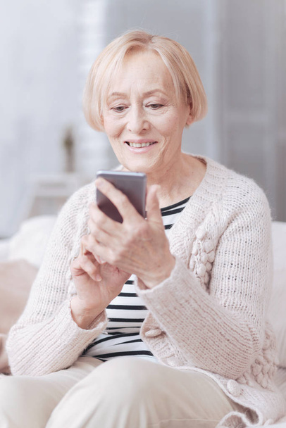 Cheerful grandma using her smartphone at home - Foto, Bild