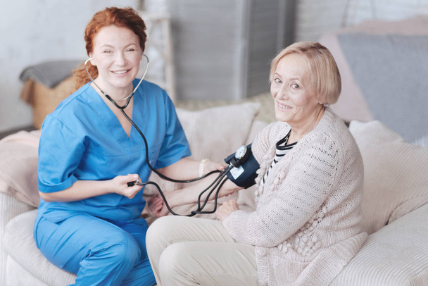 Senior lady and her nurse smiling while measuring pressure - Photo, image
