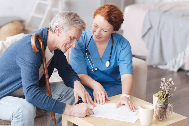 Cheerful medical worker helping patient with insurance application - Foto, imagen