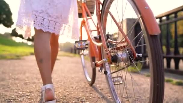 Young beautiful woman walking with a bicycle at sunset. Slow motion - Filmagem, Vídeo