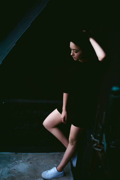 jovem com belos pés vestidos de tênis branco e vestido preto, contra um pano de fundo de paisagens urbanas
 - Foto, Imagem