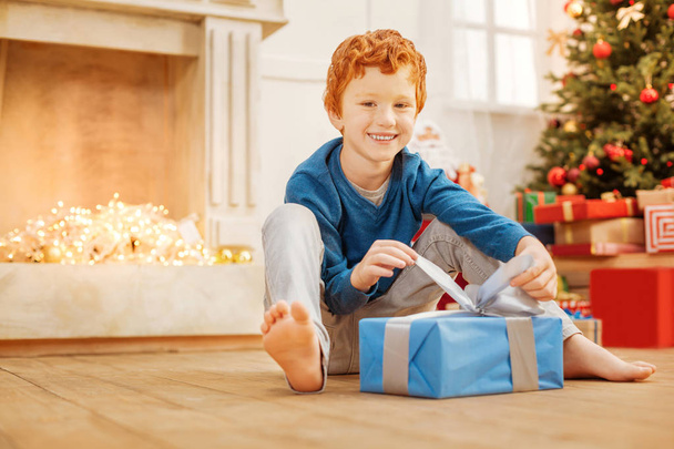 Beaming redhead boy opening his christmas gift - Foto, afbeelding