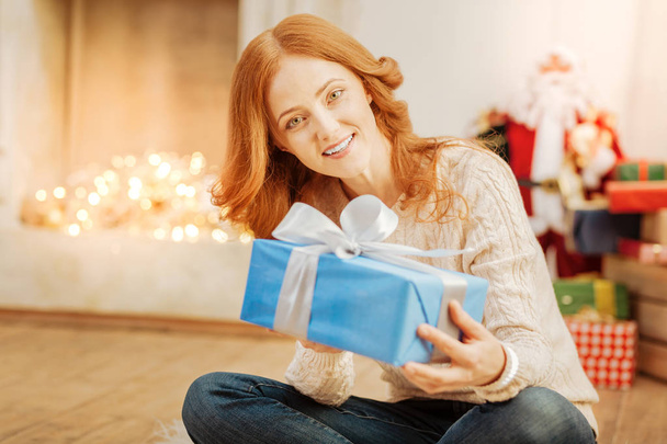 Cheerful mature lady smiling while holding christmas present - Foto, imagen