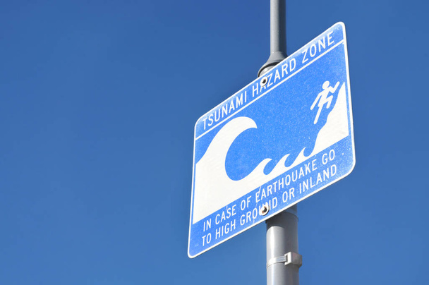 Предупреждающий знак зоны опасности цунами на голубом небе
  - Фото, изображение