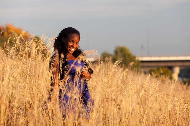 Όμορφο μαύρο κορίτσι φορώντας μπλε φόρεμα σε φθινοπωρινό τοπίο - Φωτογραφία, εικόνα