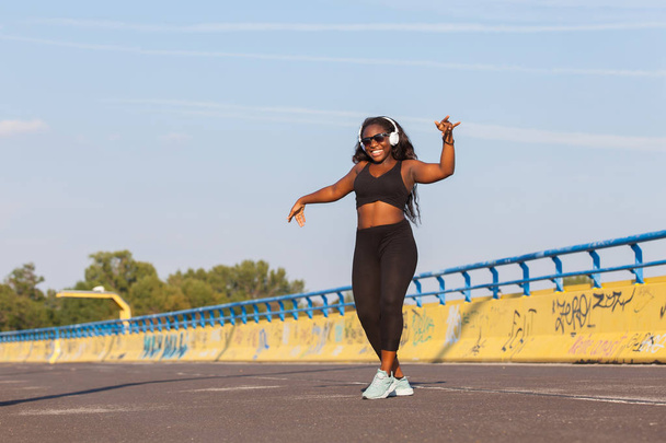 Giovane donna africana che indossa abbigliamento sportivo e ascolta musica per strada
 - Foto, immagini