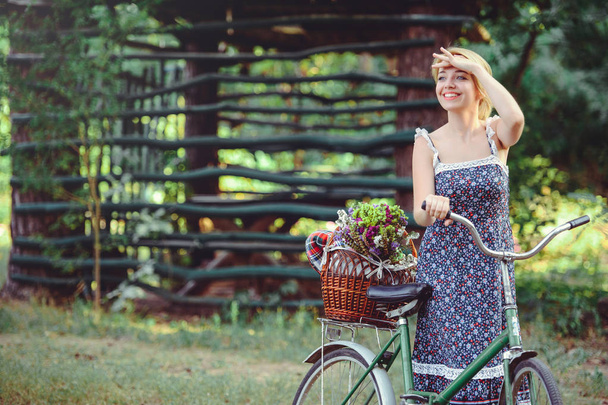 Egy egészséges nő. Szépség lány nyári élénk színek kerékpár erdő és a kosár. stílus szabadidős. Egy gyönyörű hölgy felemelte a kezét. Aranyos arca. hely a banner és a reklám - Fotó, kép