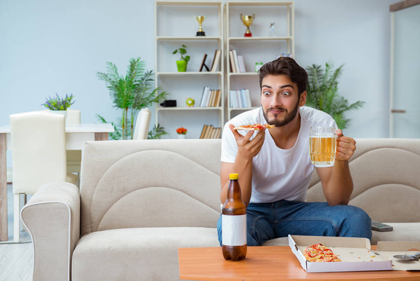Man eating pizza having a takeaway at home relaxing resting - Фото, изображение