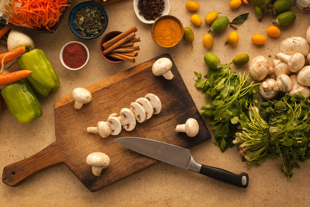 Нарізані гриби на дерев'яному столі з овочами для приготування їжі. Він
 - Фото, зображення