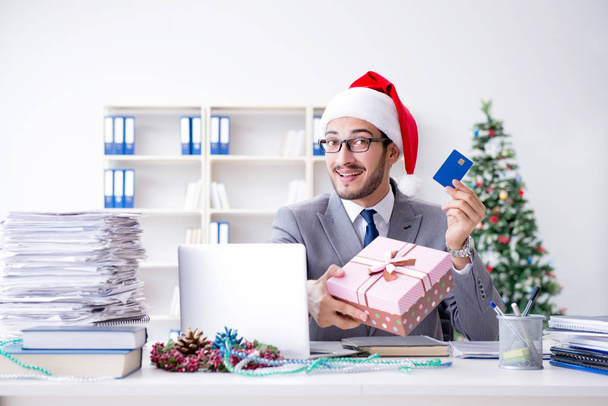 Молодой бизнесмен празднует Рождество в офисе - Фото, изображение