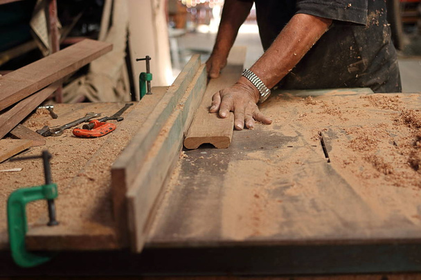 Кусок деревянной доски брится на столе маршрутизатора руками старшего плотника в столярных мастерских.
. - Фото, изображение