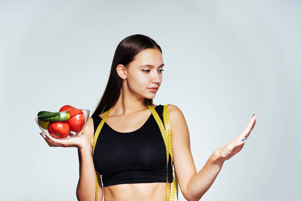 sportovní dívka v černý top uchovává informace o její postavy, drží desku s užitečné zeleniny a ovoce ve svých rukou - Fotografie, Obrázek