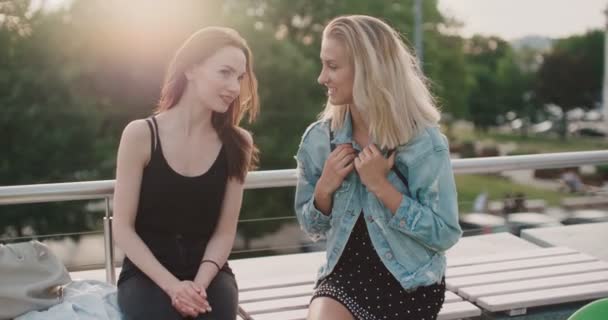 Two cheerful girls discussing latest gossip news in a city.  - Materiaali, video