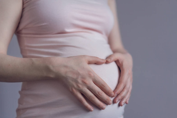 Femme enceinte touchant son ventre avec les mains - Photo, image