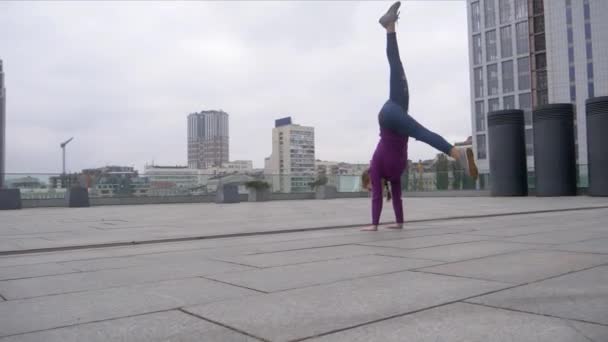Jonge aantrekkelijke vrouw doen acrobatiek met stadsgezicht op de achtergrond - Video
