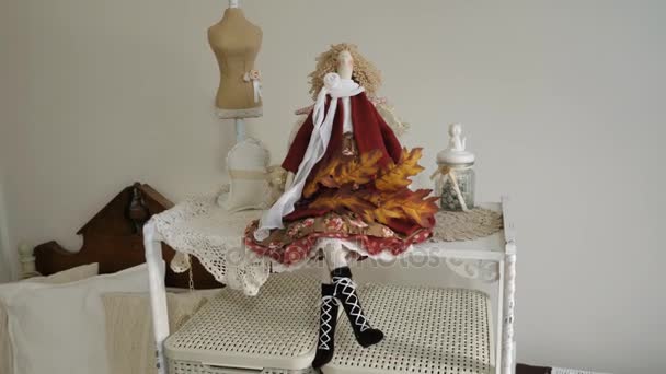 eine schöne Puppe sitzt auf einem Regal mit einem Ahornzweig. - Filmmaterial, Video