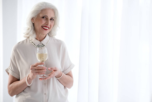 Joyful senior lady drinking alcohol beverage on celebration - Foto, Bild