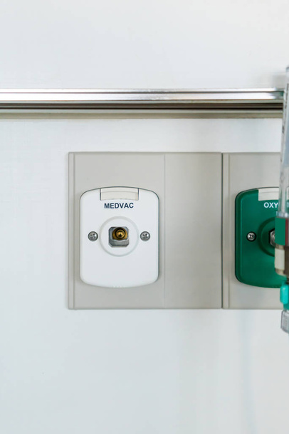 Gesloten omhoog vacuum stopcontact op de witte muur door groene zuurstof outlet  - Foto, afbeelding