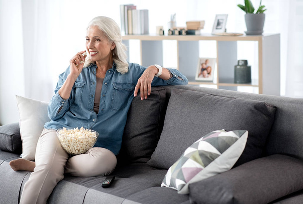 Glad senior woman watching tv at home - Фото, зображення