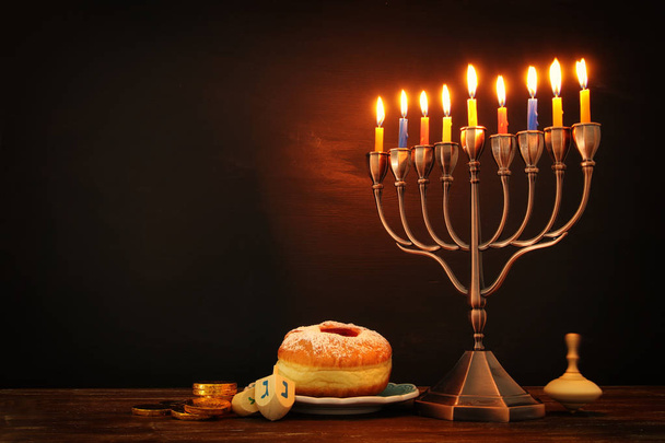 jewish holiday Hanukkah background with traditional spinnig top, menorah (traditional candelabra) and burning candles - Photo, image