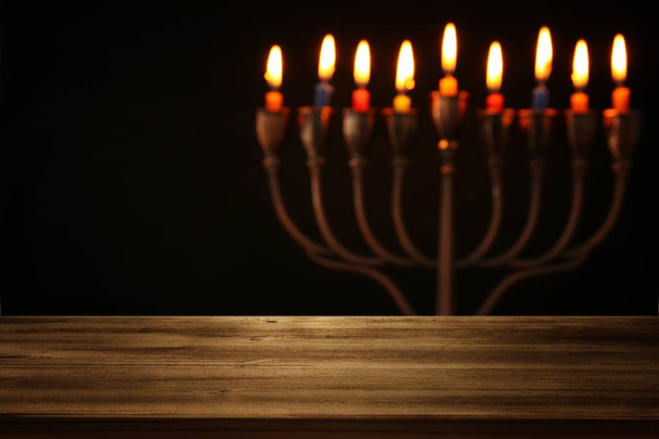 Empty wooden table in front of jewish holiday Hanukkah background with menorah (traditional candelabra). - Fotografie, Obrázek