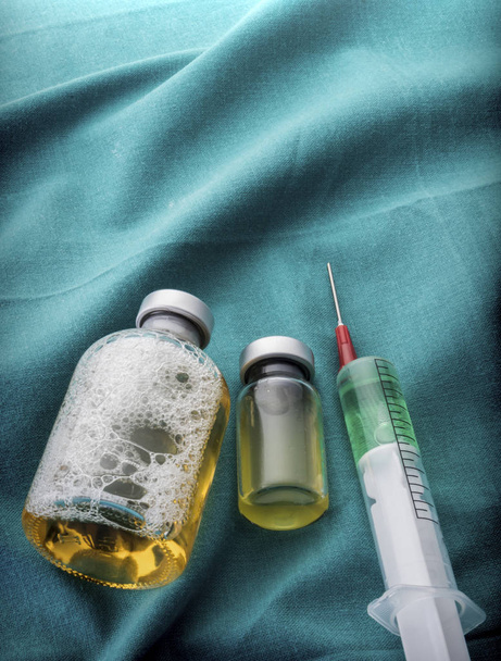 Alguns frascos para injetáveis e seringa na mesa de operação
 - Foto, Imagem