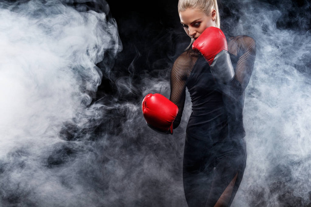 A strong athletic, woman boxer, boxing at training on the black background. Sport boxing Concept with copy space. - Foto, immagini