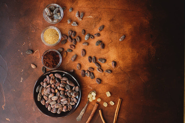 Raw cocoa beans, cacao powder and brown sugar on dark stone background - Valokuva, kuva