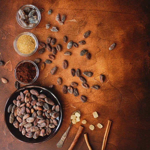 Raw cocoa beans, cacao powder and brown sugar on dark stone background - Photo, Image