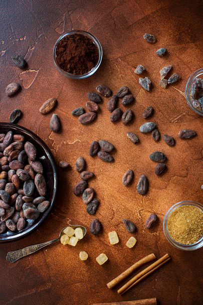 Raw cocoa beans, cacao powder and brown sugar on dark stone background - Фото, зображення