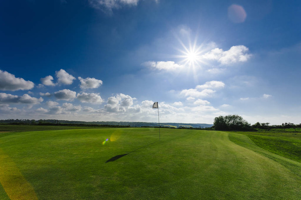 Widok zielony pole golfowe, otwór i flagi na jasny, słoneczny dzień. Sport, relaks, Rekreacja i aktywny wypoczynek koncepcja. Krajobraz lato z promienie słoneczne - Zdjęcie, obraz