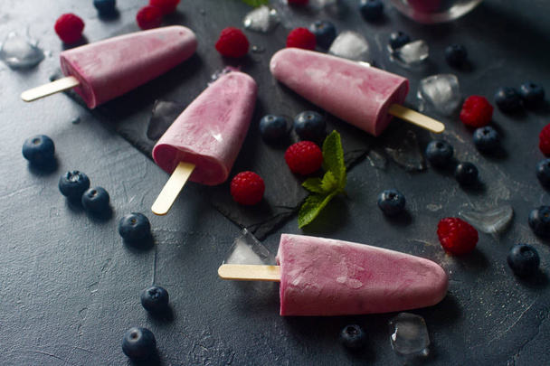Homemade frozen fruit popsicles with fresh natural raspberry and blueberry, tasty ice pops, summer food concept, selective focus - Foto, Bild