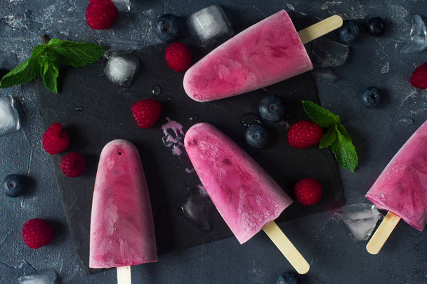 Homemade frozen fruit popsicles with fresh natural raspberry and blueberry, tasty ice pops, summer food concept, top view - Photo, image