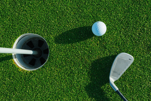 Golf club and ball on the green course. Close up. Top view. Sport, relax, recreation and leisure concept - Photo, Image