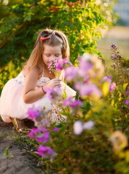 little girl beautiful smiling dancing in pink dress tutu as ballerina on sunny day happy childhood against a background of blooming summer in flowers - Foto, immagini