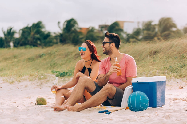 Couple drinking beer and having fun on the beach - Photo, image