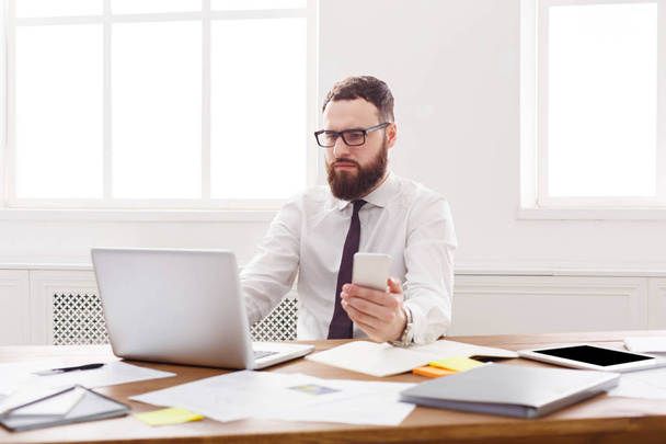 Συλλογισμένος επιχειρηματίας με το laptop στο μοντέρνο λευκό γραφείο - Φωτογραφία, εικόνα