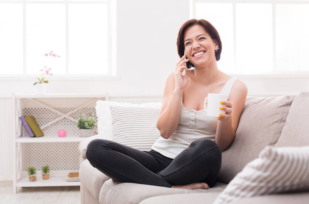 Young podekscytowany kobieta rozmawia telefon i picia kawy - Zdjęcie, obraz