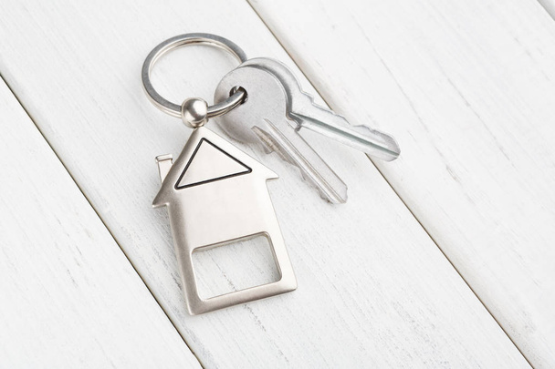 Δέσμη των κλειδιών με σπίτι σε σχήμα μπρελόκ σε λευκό ξύλο - Φωτογραφία, εικόνα