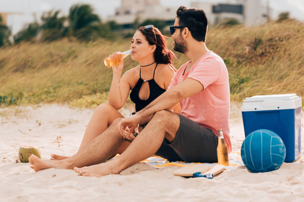 Couple drinking beer and having fun on the beach - Photo, Image