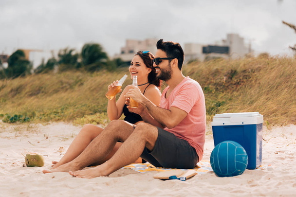 Couple drinking beer and having fun on the beach - Photo, image