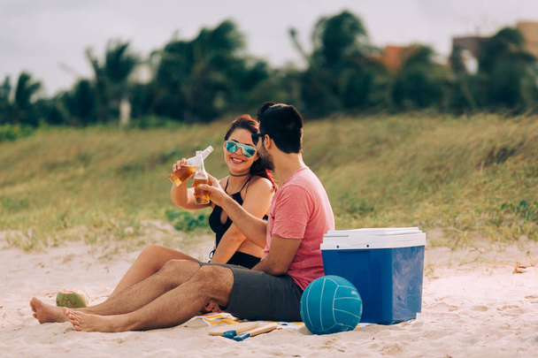Couple drinking beer and having fun on the beach - Fotoğraf, Görsel