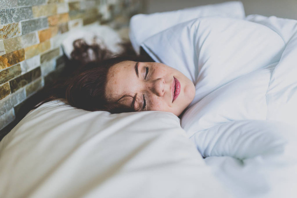 Kobieta na poduszce w łóżku z zamkniętymi oczami  - Zdjęcie, obraz