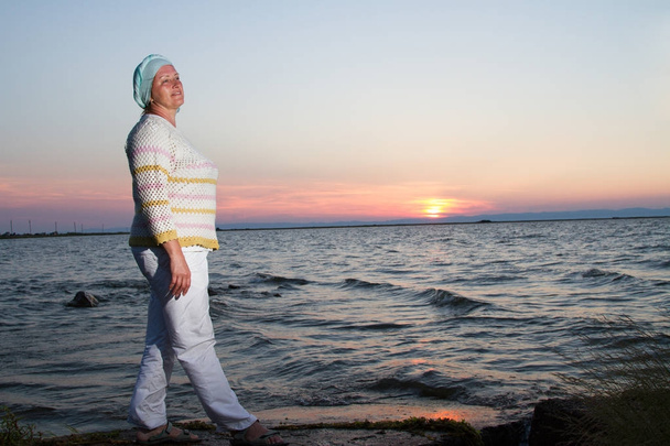 Szczęśliwa kobieta na tle zachodu słońca na plaży - Zdjęcie, obraz
