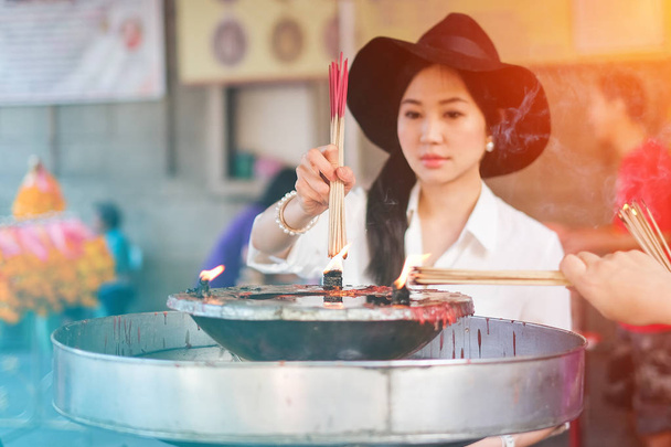 Woman holding burning incense sticks in chinese temple - Photo, Image