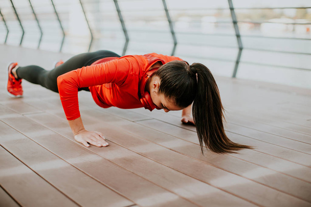 Женщина делает упражнения на доске на набережной
  - Фото, изображение