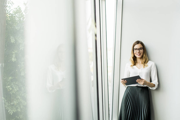 Молода бізнес-леді стоїть провід планшет в офісі
  - Фото, зображення