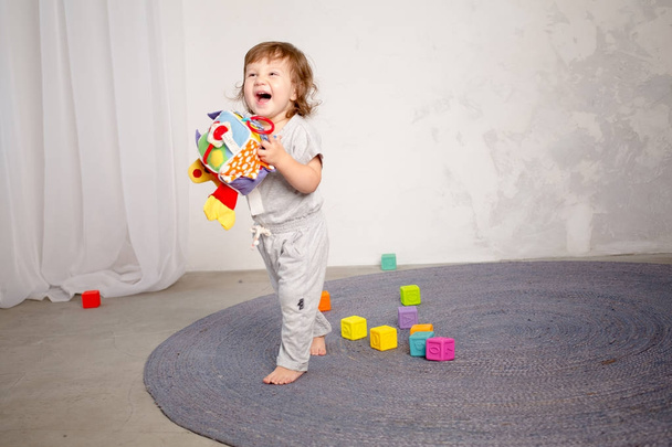 kleines glückliches Mädchen spielt mit Spielzeug auf dem Fußboden. - Foto, Bild