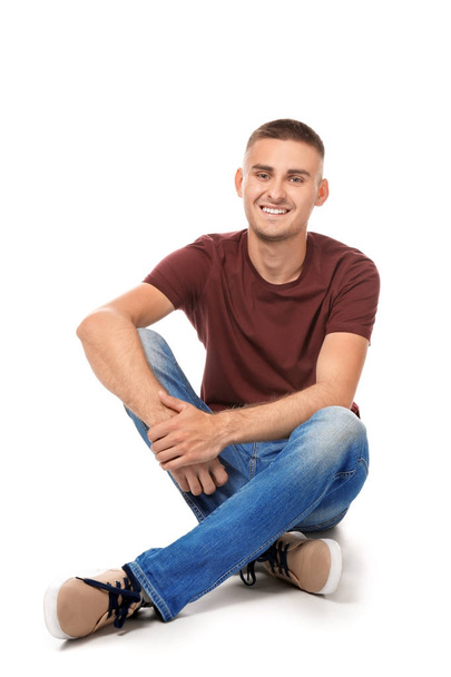 Handsome young man sitting against white background - Zdjęcie, obraz